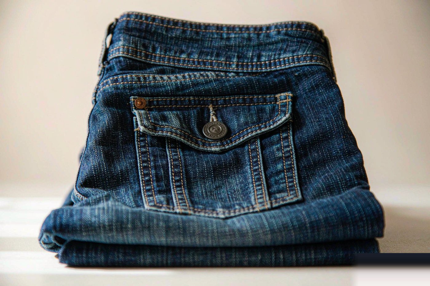 Close view of denim stitching, a rivet and the inside of a pocket